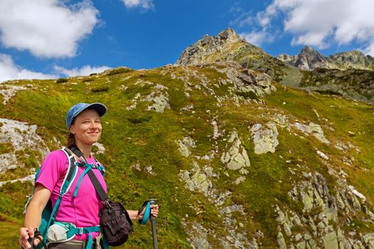 Happy woman with backpack standing on a rocky mountain background. Tatra Mountains, Slovakia, Europe