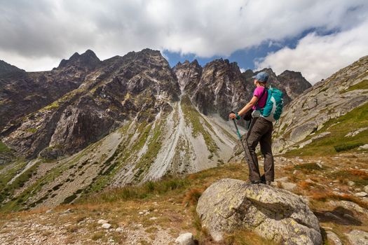 Happy woman with backpack standing and looking on high rocky peaks in Tatra Mountains, Slovakia, Europe