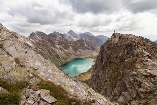 Hiking woman standing on high peak and pointing on rocky Tatra mountains, near Hlincovo Pleso lake