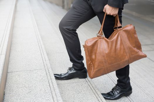 Businessman with briefcase brown leather bag walking upstairs ,Fighting against obstacles Climb up to Successful finish concept.