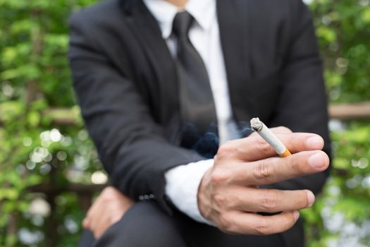 businessmen cigarettes for smoking sit in the park in the smoking zone area.