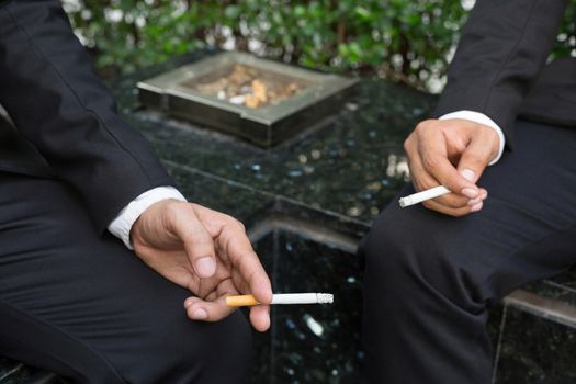 Businessman two people smoking cigarette sitting in the smoking area zone.