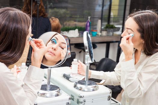 White woman removing makeup in front of mirror at beauty salon