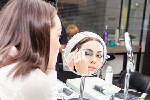 White woman removing makeup in front of mirror at beauty salon