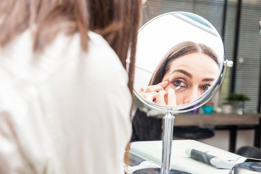 White woman removing makeup in front of mirror at beauty salon