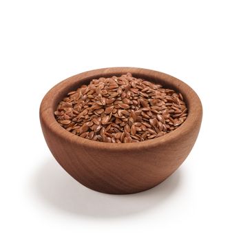 Ground or crushed brown flax seed or linseed in a wooden bowl, isolated on white