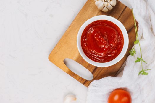 Delicious ketchup in bowl with ingredients on kitchen table, top view