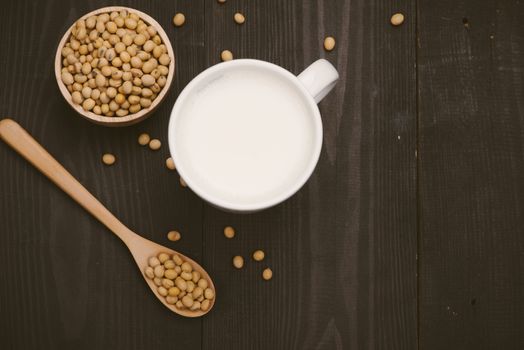 Glass with soy milk and soy bean on wooden background