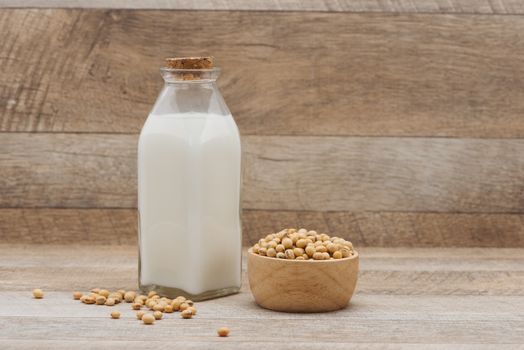 Bottle of soy milk and soybean on wooden table