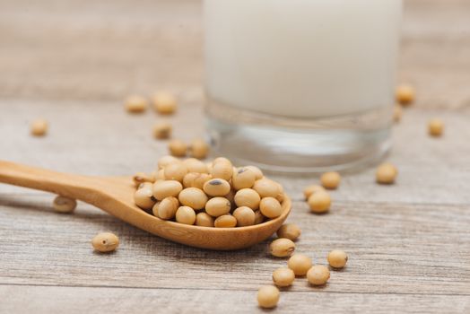 Soy beans in spoon on wooden background