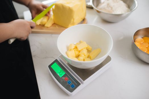Cropped image of female chef cutting butter in kitchen