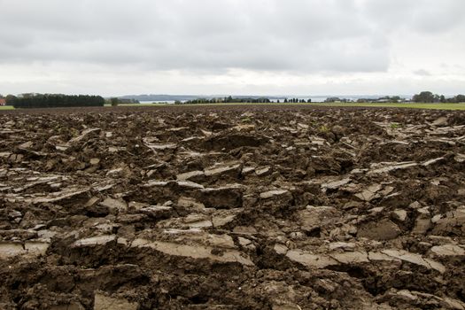 Dark brown dirt field on a cloudy day in autumn.