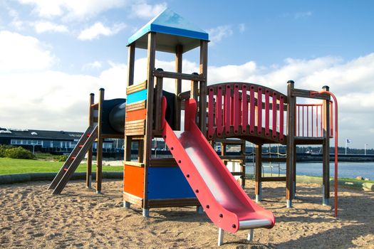 Wooden red and blue playground on sand on a sunny day.