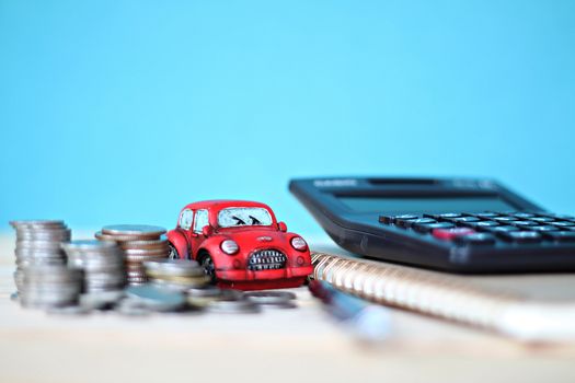 Business, finance, saving money or car loan concept : Miniature car model, coins stack, calculator and notebook paper on office desk table