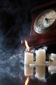 Vintage still life with extinguished candles near old clock