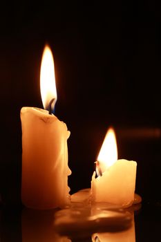 Closeup of two lighting candles against dark background