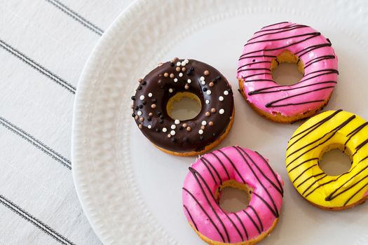 assorted donuts with chocolate frosted, pink glazed and sprinkles donuts.