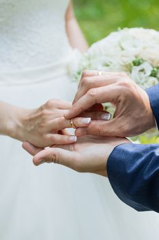 Wedding day. The groom places the ring on the bride's hand.