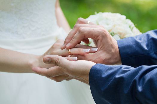 Wedding day. The groom places the ring on the bride's hand.