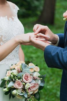 Wedding day. The groom places the ring on the bride's hand.