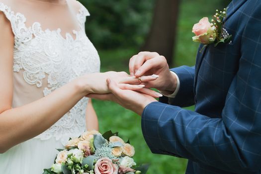 Wedding day. The groom places the ring on the bride's hand.