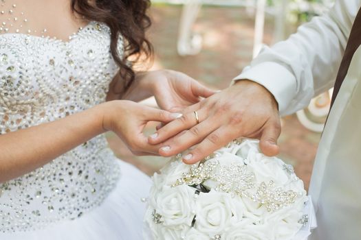 Wedding day. The groom places the ring on the bride's hand.