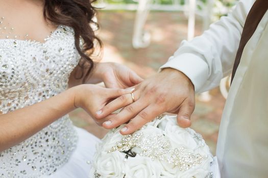 Wedding day. The groom places the ring on the bride's hand.