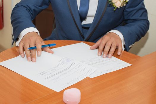 Young couple signing wedding documents. Focus on hand.