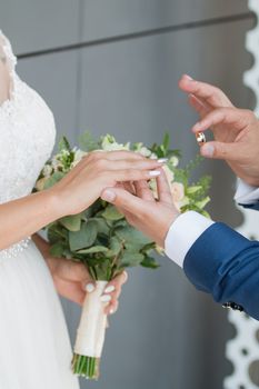 Wedding day. The groom places the ring on the bride's hand.