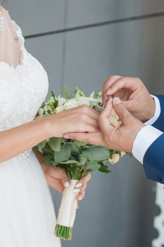 Wedding day. The groom places the ring on the bride's hand.