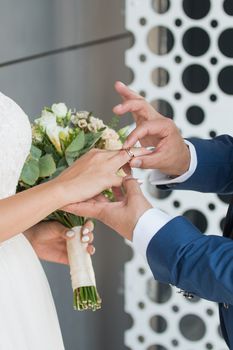 Wedding day. The groom places the ring on the bride's hand.