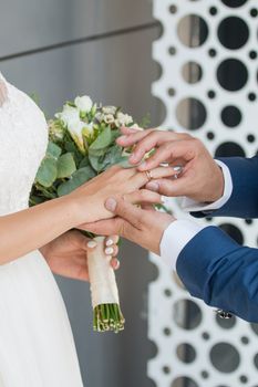 Wedding day. The groom places the ring on the bride's hand.