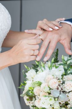 Wedding day. The groom places the ring on the bride's hand.