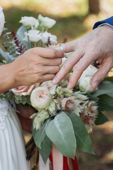 Wedding day. The groom places the ring on the bride's hand.