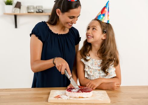 Shot of a mother and daughter cuting the cutting the birthday cake