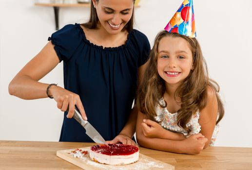 Shot of a mother and daughter cuting the cutting the birthday cake