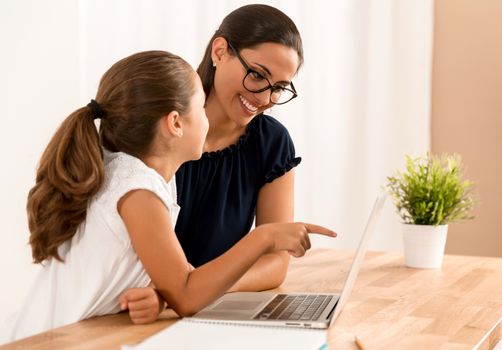 Young mother helping her daughter with homework at home