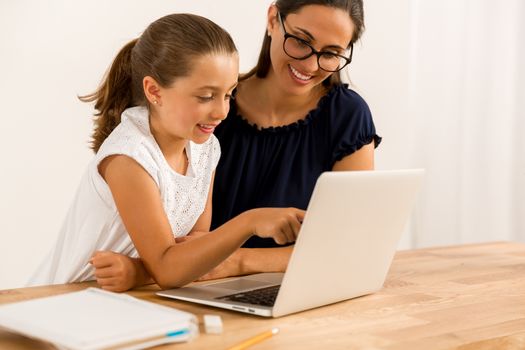 Young mother helping her daughter with homework at home