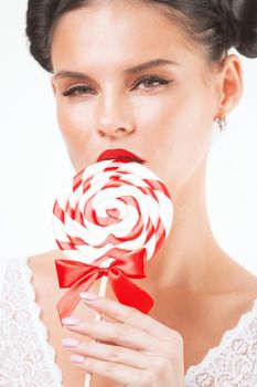 Close-up of beautiful girl's lower part of face. lips are sliding over big lollipop.