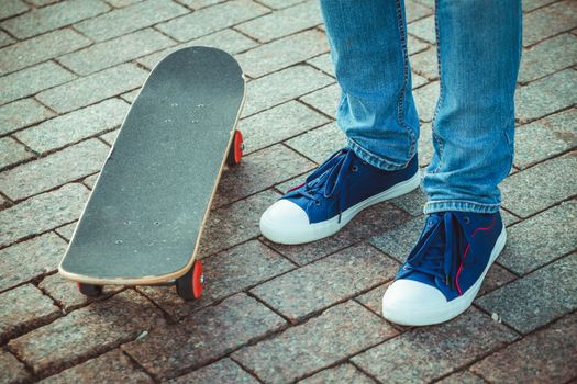 male feet in blue trainers and skateboard close up.