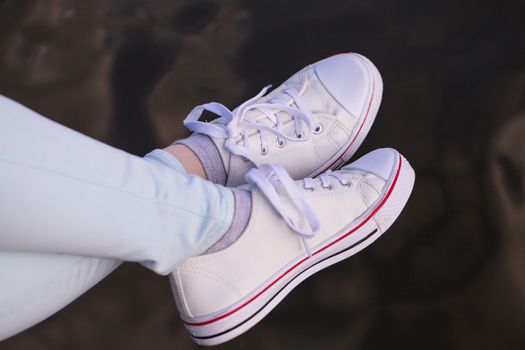 female feet in white sneakers close up