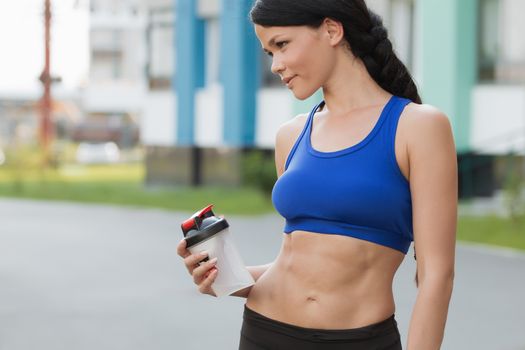 Fitness beautiful woman drinking water and sweating after exercising on summer hot day in beach. Female athlete after work out.