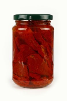 Close up of one glass jar of pickled red sundried cured tomatoes in oil with green lid over white background, low angle side view
