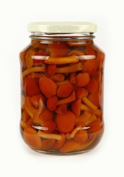 Close up of one glass jar of pickled small brown honey fungus Armillaria mushrooms over white background, low angle side view