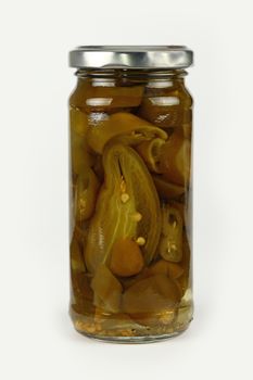 Close up of one small glass jar of pickled cut sliced green hot jalapeno chili peppers over white background, low angle side view