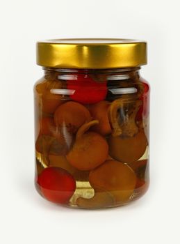 Close up of one glass jar of pickled red and green hot cherry chili pepperoncini peppers with golden lid over white background, low angle side view