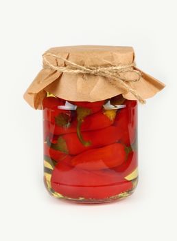 Close up of one glass jar of pickled red hot cherry chili pepperoncini peppers with kraft paper parchment decoration and twine over white background, low angle side view