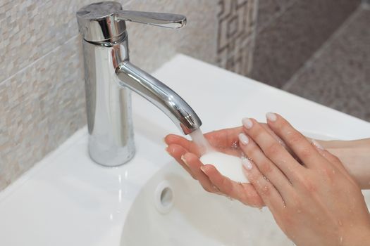 Washing of hands with soap under running water.