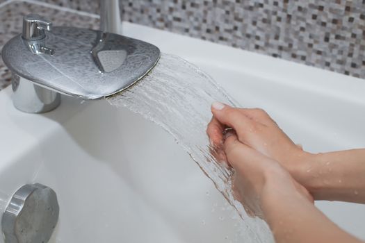 Washing of hands with soap under running water.