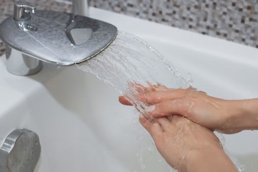 Washing of hands with soap under running water.